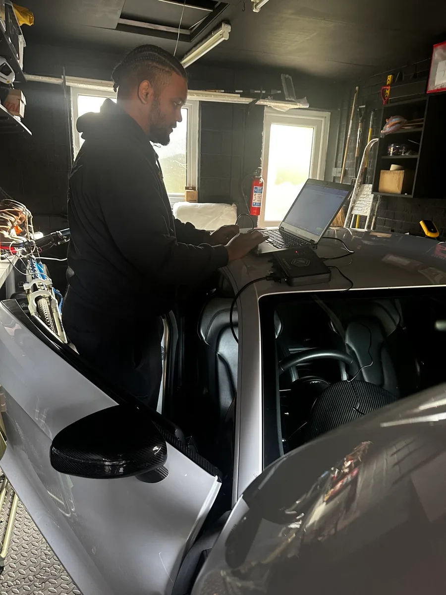 Adam using ECU tuning software beside an Audi R8